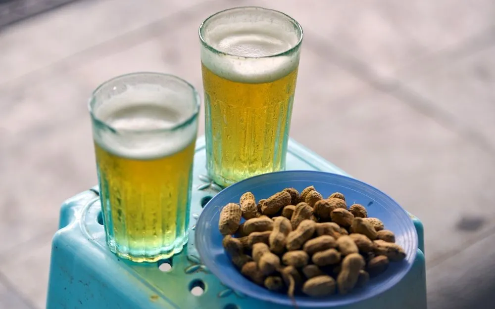 Bia Hoi vietnamita fresca con snack locali in un incrocio Bia Hoi