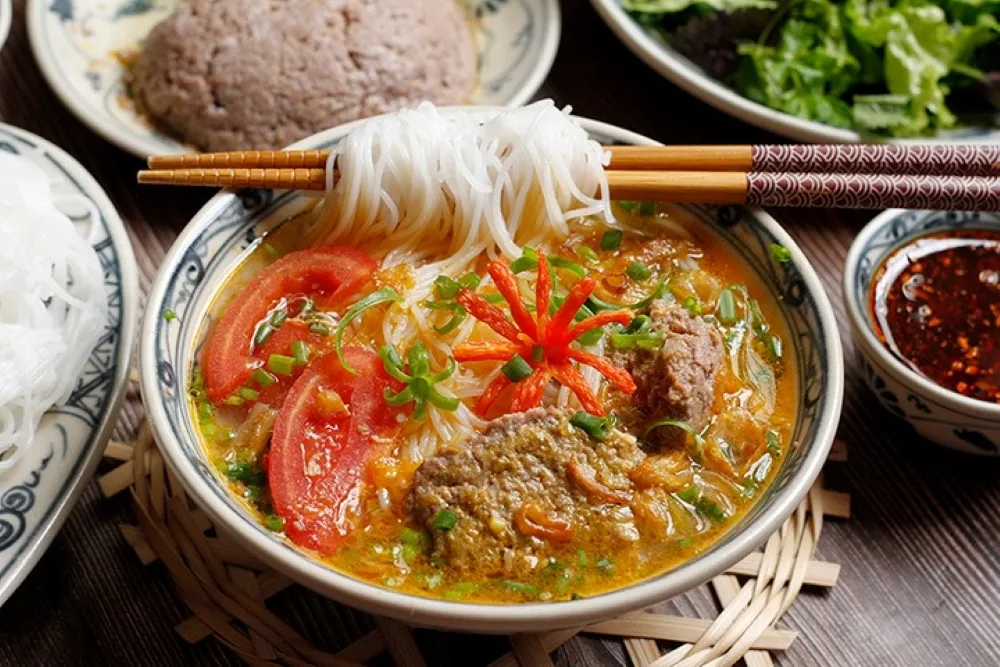 Bowl of bun rieu with tomato crab broth, fried tofu, and vermicelli noodles