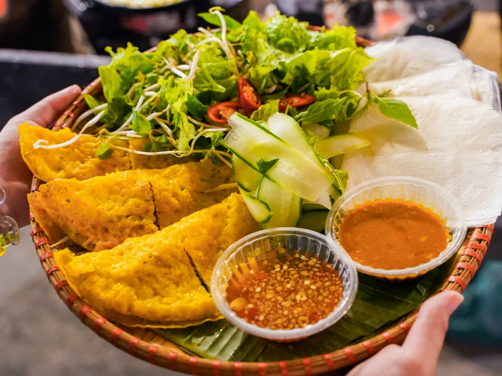 Tasting vietnamese pancake with salad and fresh herbs.
