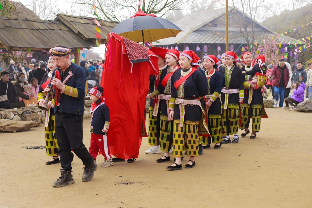 Red Dao men and woman in elaborately embroidered traditional dress with iconic red headdress in Ha Giang Vietnam