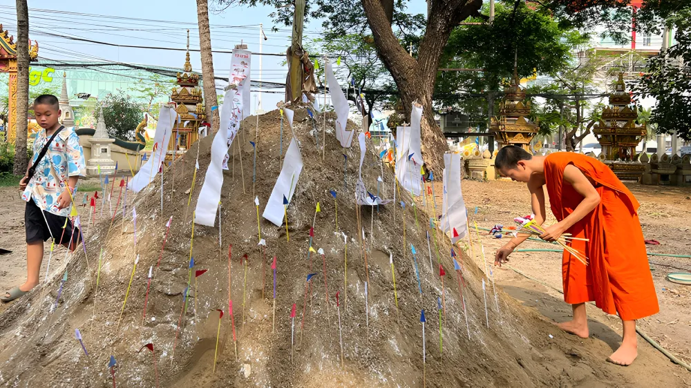 Decorated sand stupas offered at a Buddhist temple courtyard during Boun Pi Mai celebrations