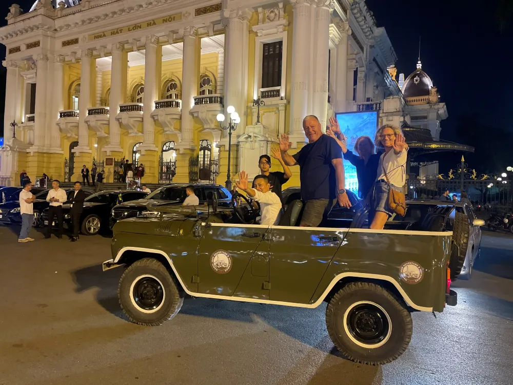 Guida locale che condivide storie con i turisti in un tour in Jeep scoperto d'epoca ad Hanoi