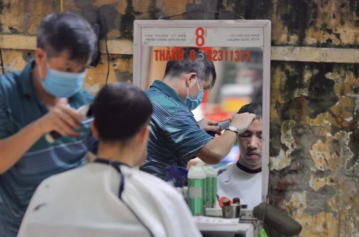 Tagliarsi i capelli dai barbieri sul marciapiede quartiere antico hanoi
