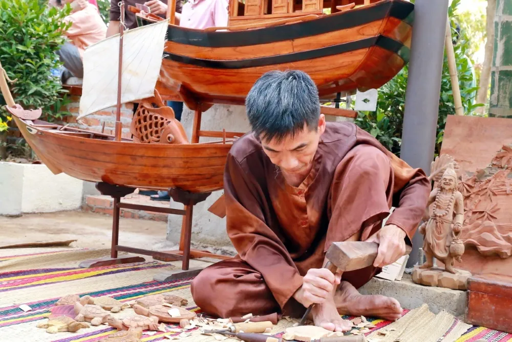 Skilled craftsman working on intricate wood carving at Kim Bong