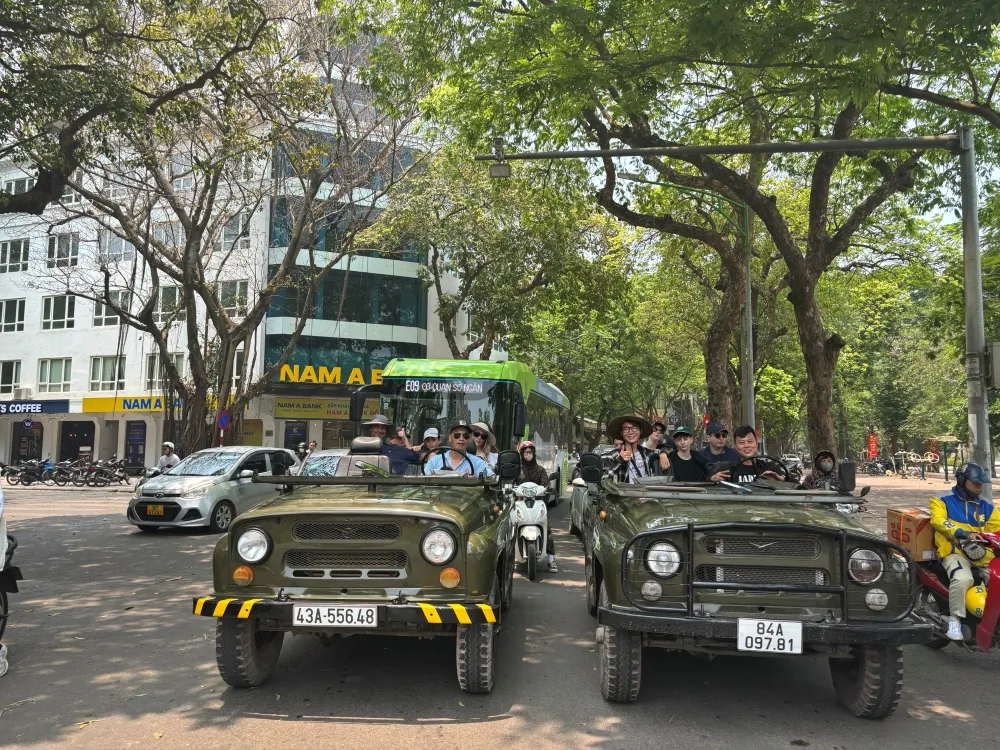 Tourists on an open-air Hanoi jeep tour exploring the city streets