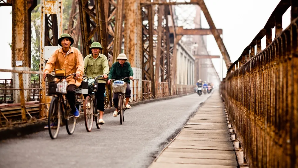Cyclists riding across historic Long Bien Bridge in Hanoi
