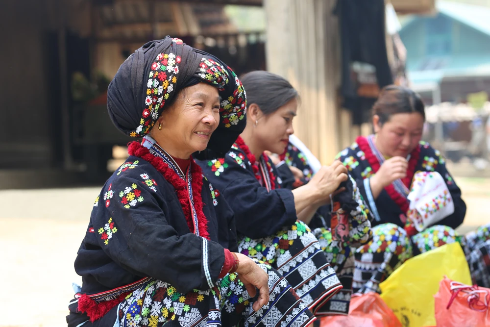 Femme Dao Rouge brodant un costume traditionnel &agrave; la main