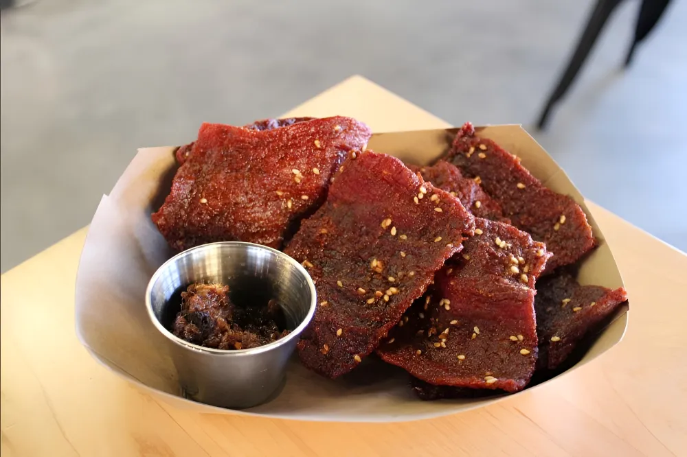 strips of savoury Sien Savanh Laotian dried beef grilled and served with sticky rice and a spicy jaew dipping sauce