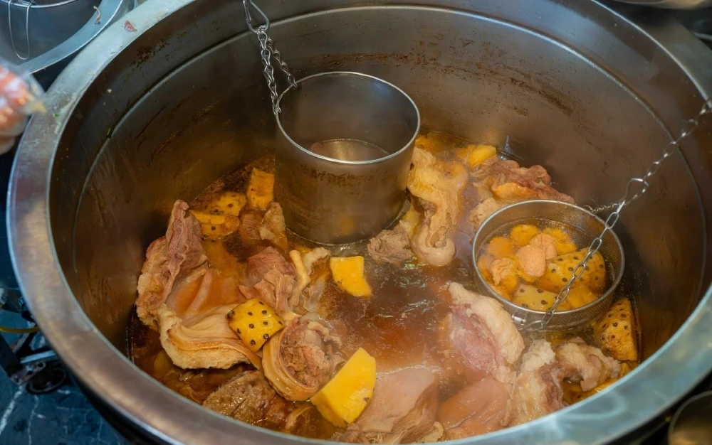 Rich and fragrant Bun bo Hue broth simmering with lemongrass, annatto oil, and traditional Vietnamese spices
