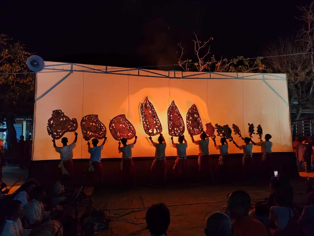Traditional Khmer shadow theatre performance featuring large Sbek Thom leather puppets projected onto a backlit white screen in Cambodia