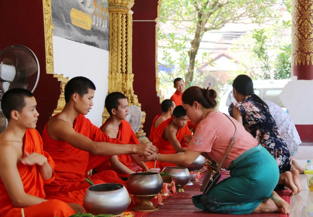 Traditional Baci ceremony in Laos showing colourful cotton threads being tied around a wrist for good luck