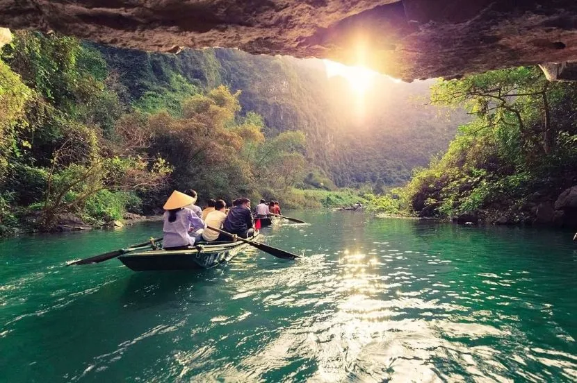 small boat passing through limestone caves in ninh binh