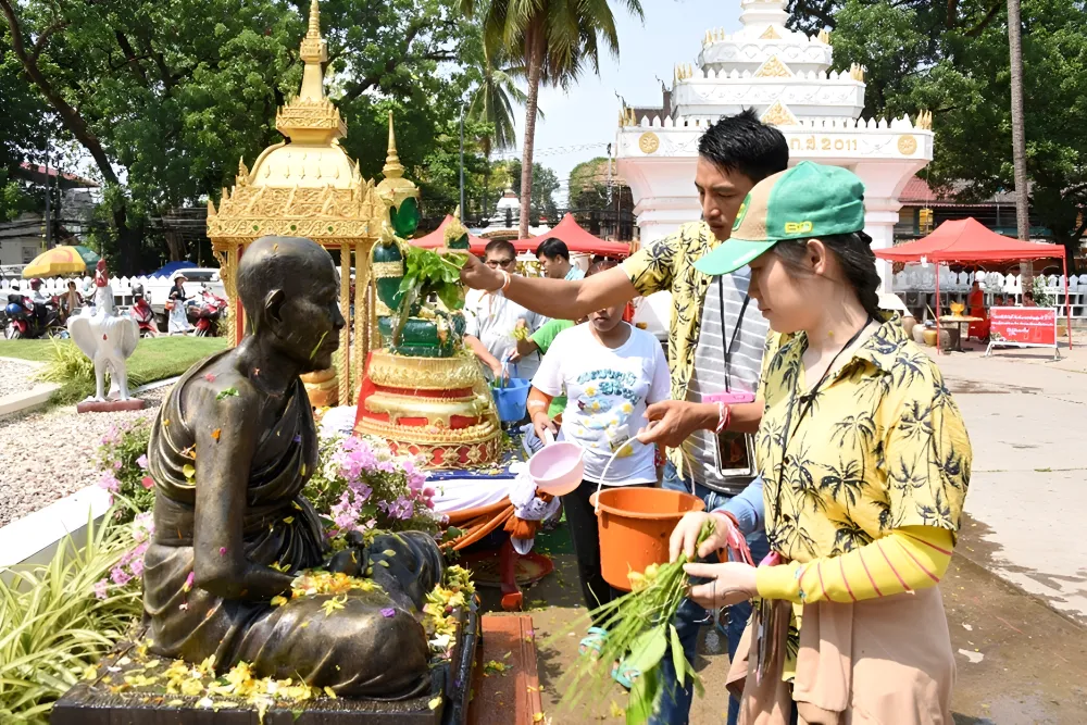 Local devotees performing the Buddha statue bathing ceremony with scented water during Pi Mai Lao