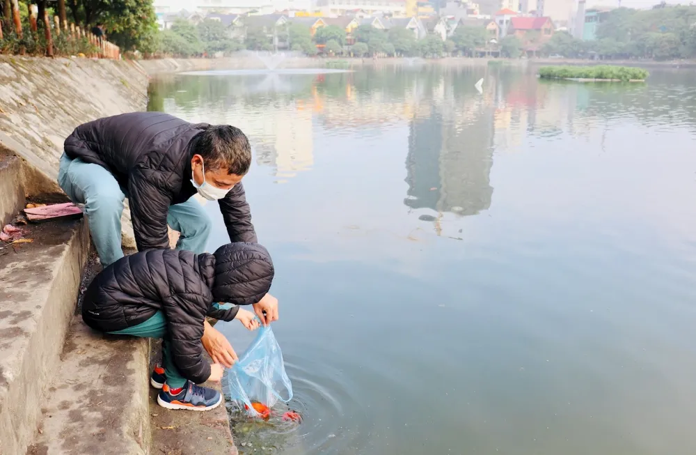 les Vietnamiens relâchent des carpes vivantes dans une rivière ou un étang